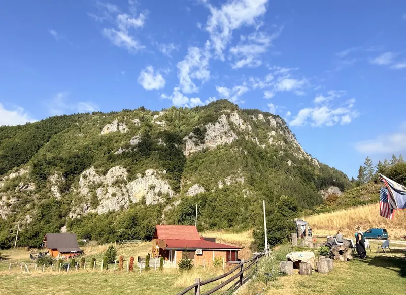 Meadow below the cliffs with small cabins and camping gear
