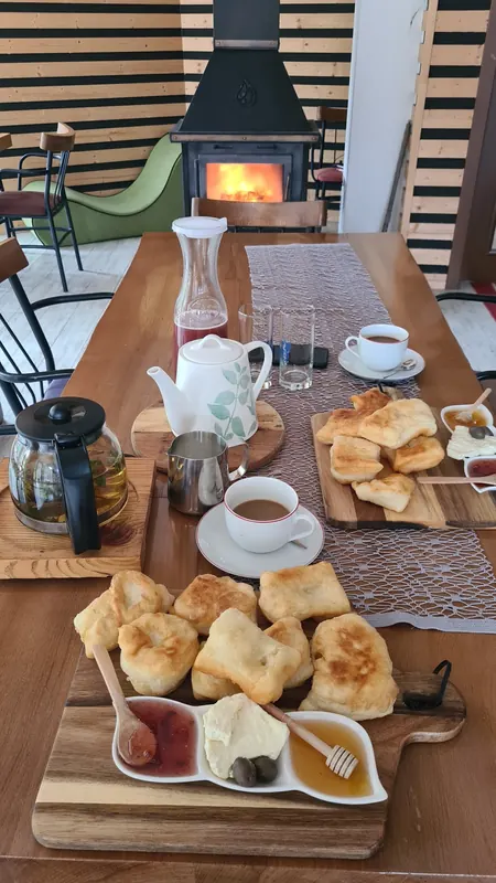 Breakfast of fried dough, cheese, jam and honey on a long table by the fireplace