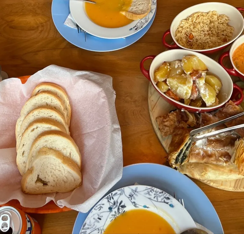 Dinner spread of soups, bread, salad and baked dishes on a wooden table