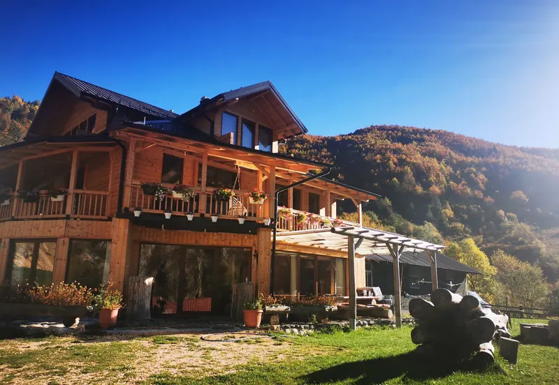 The guesthouse in autumn sun, wooded hills turning gold behind it