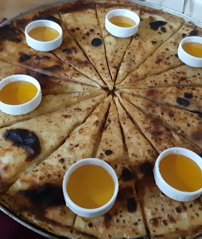 A large home-baked pie with small bowls of honey